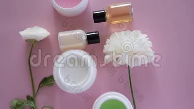 在新鲜的粉红色背景下，可以看到不同的卫生/化妆品产品和鲜花。 健康美容治疗